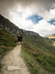 Fototapeta na wymiar Hikers on the trail in the Bucegi Mountains against a dramatic sky.