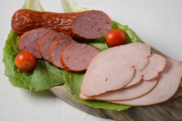 Sliced spicy smoked beef/ pork sausage and turkey pastrami slices. With lettuce leaf and basil,cherry tomatoes.