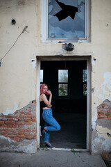 Fototapeta na wymiar Young funky teenage girl with pink hair holding lollipop candy in abandoned building.