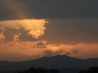 foto de atardecer con el sol tras una nube, dejando salir un rayo de luz al cielo