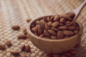 Fresh almonds nut in wooden bowl on Water hyacinth placemats.