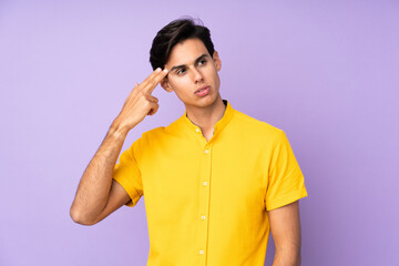 Man over isolated purple background with problems making suicide gesture