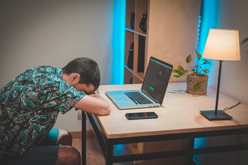 Young man tired of too much time working on laptop at home. Working late at night. Handsome man...