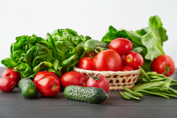 Fresh cucumbers, tomatoes, green peas, and boston salad on gray wooden table. Healthy/vegetarian/vegan diet concept