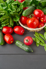 Fresh cucumbers, tomatoes, green peas, and boston salad on wooden table, top view. Healthy/vegetarian/vegan diet concept
