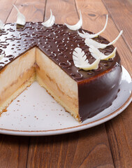 Cut chocolate cake on plate on wooden table
