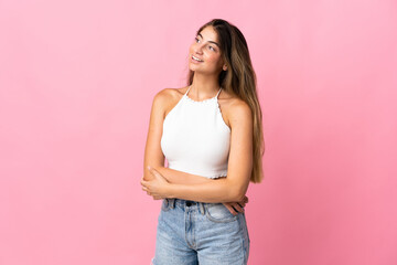 Young caucasian woman isolated on pink background looking to the side and smiling