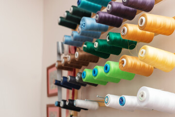 Skeins of colored thread hang on the wall in a sewing workshop. Close-up, selective focus with a shallow depth of field. Horizontal frame, space for text. The concept of business, and Hobbies.