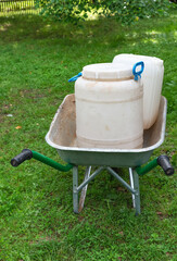 A dirty garden cart with white dirty plastic flasks on a farm on a Sunny summer day. Close-up, selective focus.