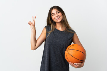 Young woman playing basketball isolated on white background smiling and showing victory sign