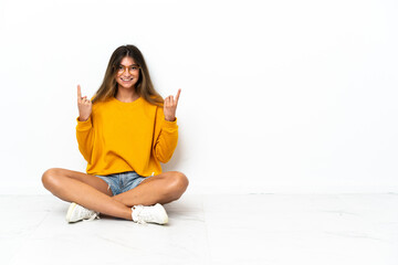 Young woman sitting on the floor isolated on white background pointing up a great idea