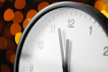Obraz na płótnie Canvas New Year eve concept with alarm clock against blurred garland