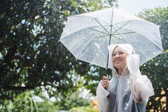 Rainy day asian woman wearing a raincoat outdoors.