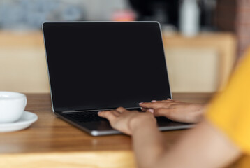 Fototapeta na wymiar Unrecognizable girl typing on laptop at cafe