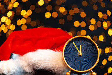 New Year eve concept with alarm clock against blurred garland
