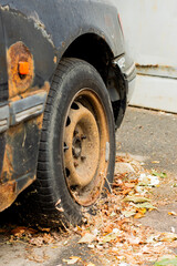 Fototapeta na wymiar An old, rusty, broken-down car stands on the asphalt on an autumn day.