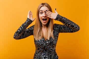 Good-humoured white girl having fun on yellow background. Indoor photo of jocund blonde lady making funny faces.