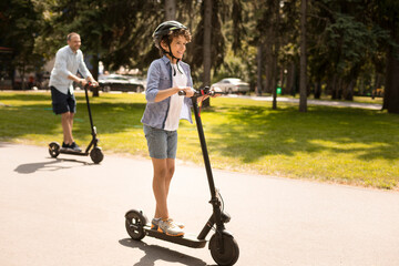 Happy guy with dad having ride on electric kick scooter