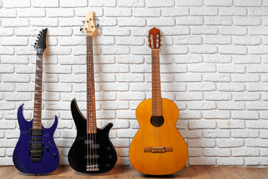 Set of guitars on the floor against white brick wall © fotofabrika