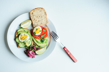 healthy vegetarian breakfast, avocado toast with cucumber, eggs, tomato and greean salad on wholegrain bread