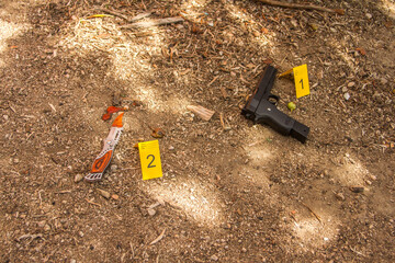 close-up of a crime scene with yellow numbered cards the police tape with the words do not pass and the weapons such as knife and gun used for the crime