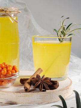 Tea buckthorn in jar and glass, piala with berries on white table. Close up.
