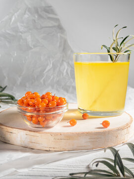 Glass of buckthorn tae and piala with berries on white table