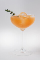 Cocktail with ice crust and orange liqueur in a tall glass, decorated with rosemary.