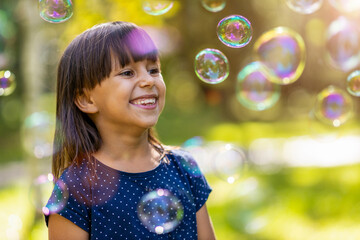 Girl playing with soap bubbles outdoors
