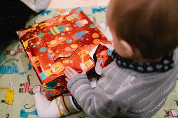Kind packt erstes Weihnachtsgeschenk aus
