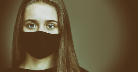 Portrait of a young girl in a black medical mask in a restrained way. The concept of protection...