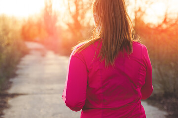 Back of woman enjoys running outdoors in park or in the countryside.