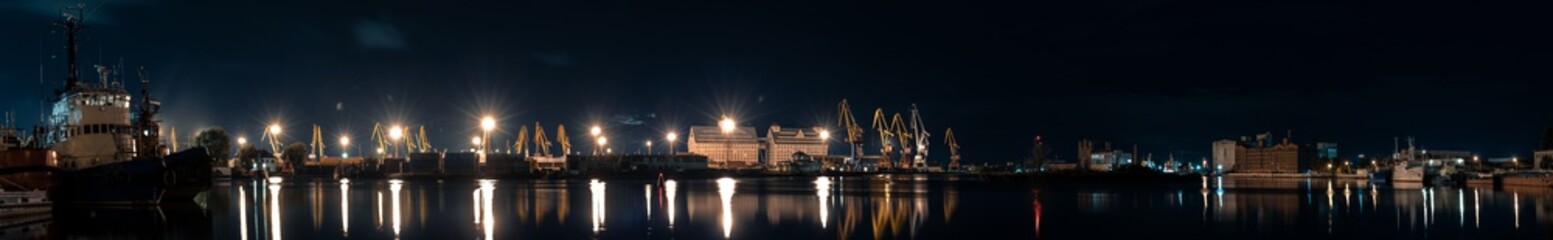 Fototapeta na wymiar panorama of night port on the river with a ships and cranes