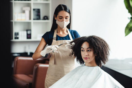 African american woman getting haircut from master in protective mask, free space
