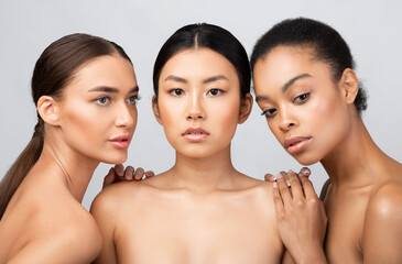 Three Beautiful Multiethnic Models Girls Posing Shirtless Over Gray Background