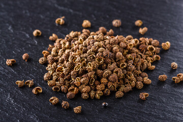 Sichuan pepper on a dark stone background