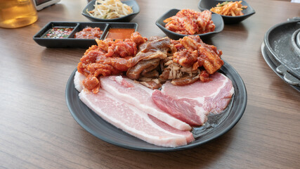 raw beef and pork slice on dish for grill with set of sauce and side dishes on background
