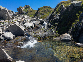 Panoramic view of alpine landscape with a small waterfall.