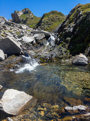 Panoramic view of alpine landscape with a small waterfall.