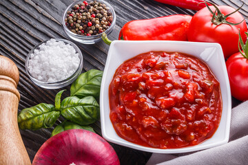 Fresh tasty tomato sauce on rustic wooden background