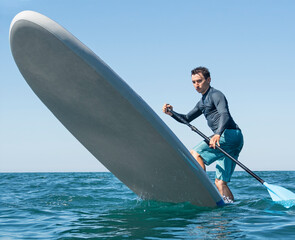 Man making pivot or step back turn trick on stand-up paddle board. Extreme sport activity