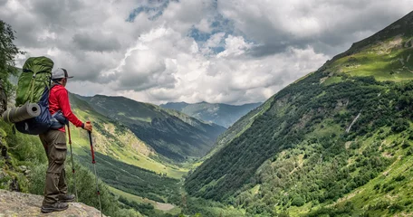 Gardinen Olive Active man with backpack and camping equipment at Imereteinka river valley background in Karachay-Cherkess, Russia  © lilkin