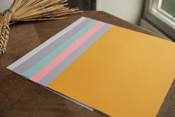 Multi-colored sheets of paper lie on a wooden table. Dry ears of wheat. Color testing concept. Selective focus.
