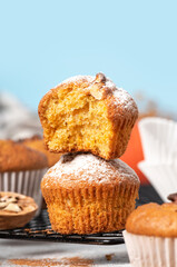Freshly baked pumpkin muffins and walnuts, cinnamon and nutmeg on a blue background. Free space for text. Autumn or winter food. Sweet seasonal pumpkin baked goods. Copy space.
