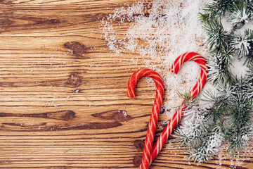 Winter festive background with fir tree branches, snow and candy canes