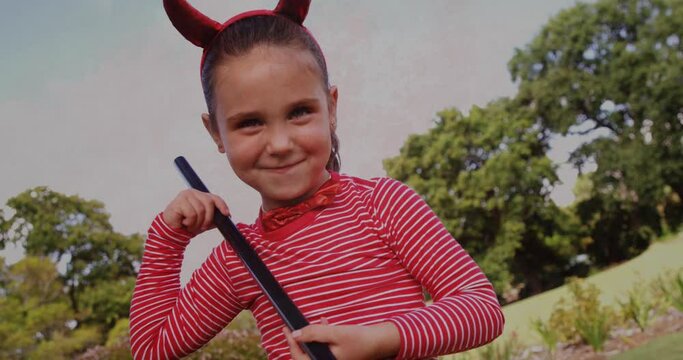 Girl wearing devil costume in park against flickering background