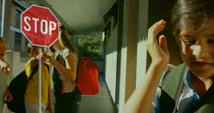 Stop sign over kids making fun of school boy in school against flickering background
