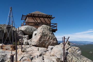 Fototapeta na wymiar A square wooden building at a top of a bare rock outcropping overlooking the mountain range below, Black Mountain Lookout, Bighorn National Forest, Wyoming