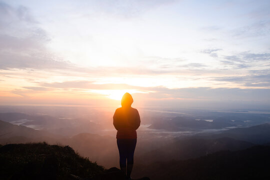 Silhouette women standing on cliff and see sun up.Photo concept active and nature background.