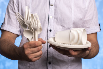 biodegradable cornstarch forks, spoons, plates and glasses in male hands. close-up. eco friendly...